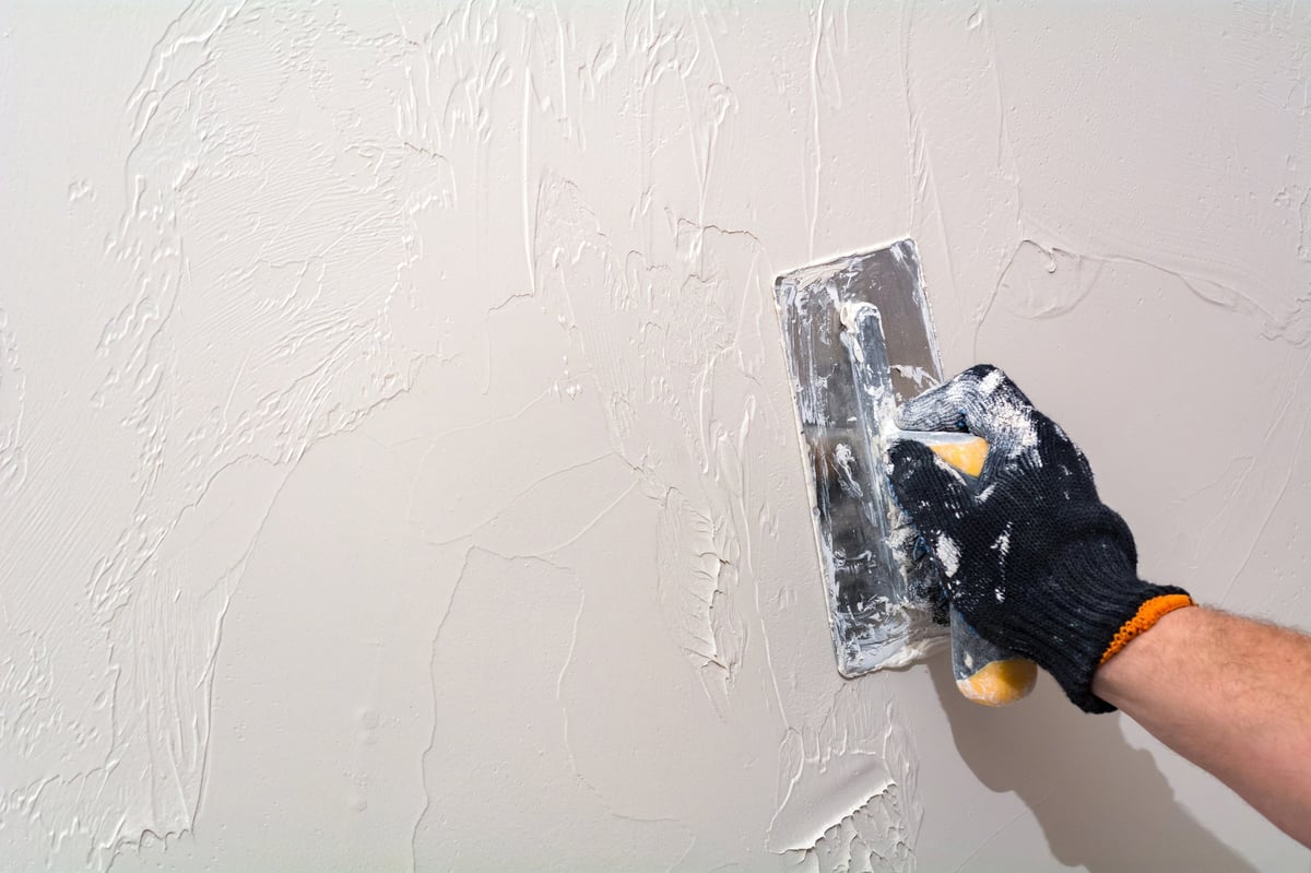 Master plasterer working on wall with repair tool in apartment