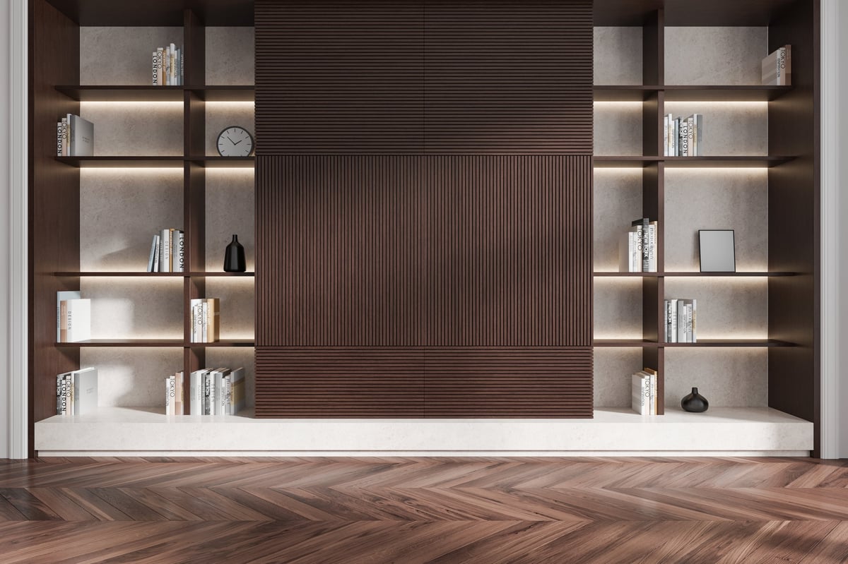 Wooden bookshelf with books and decor, featuring built-in lighting on a herringbone wood floor