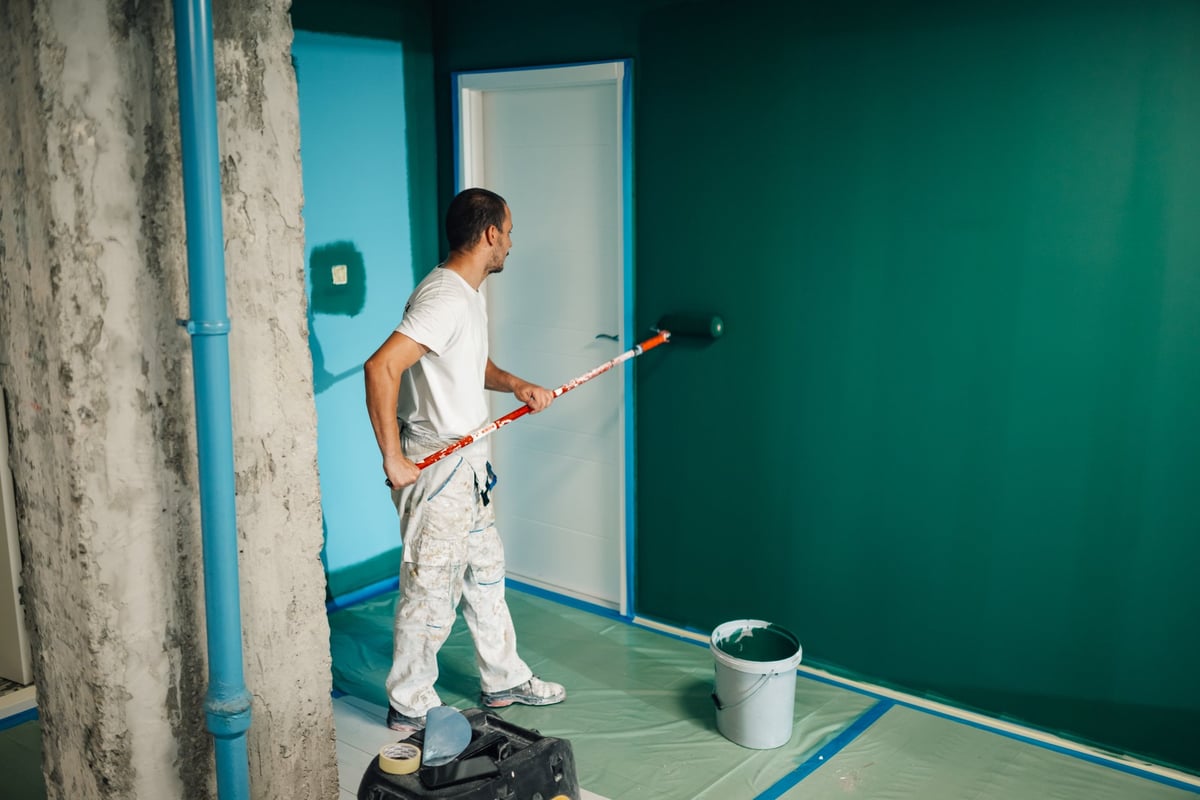 Professional painter applying paint on wall in modern home