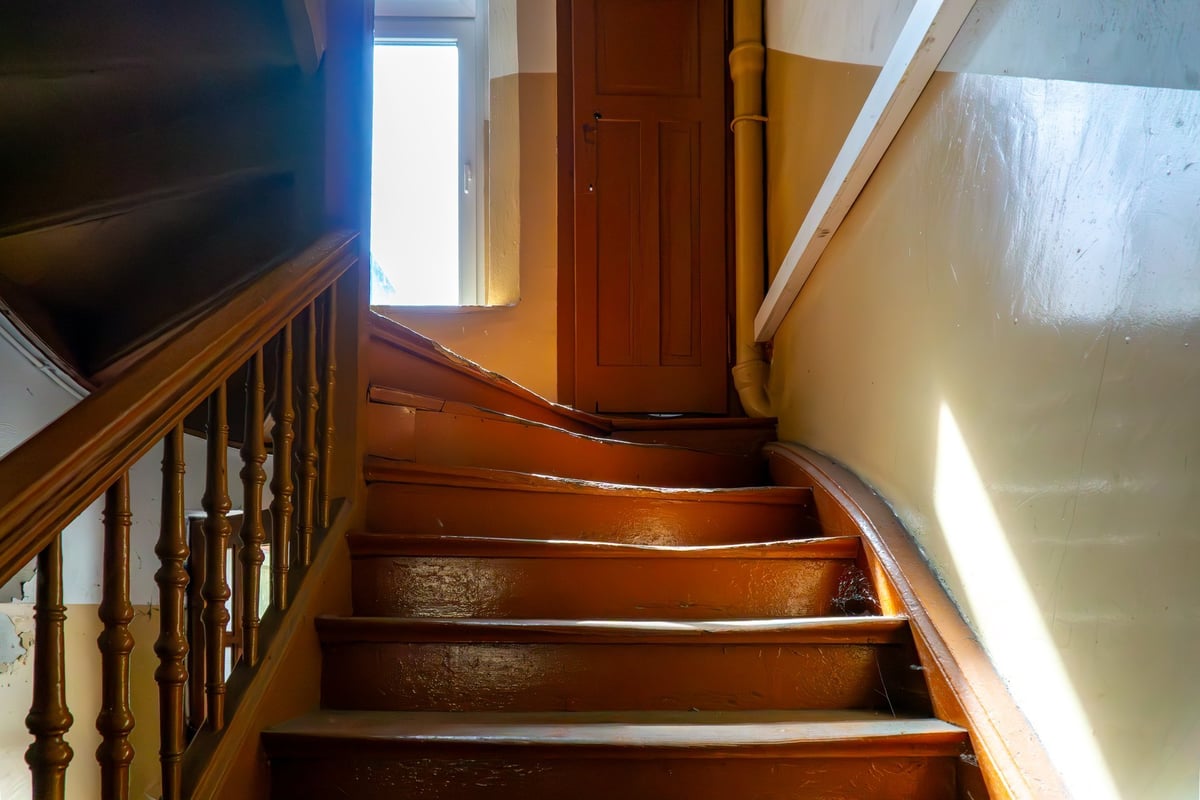Wooden staircase in a tenement house with balustrade and window