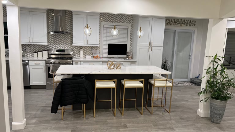 Modern kitchen with gray cabinetry, black island with seating, stainless steel appliances, and pendant lighting