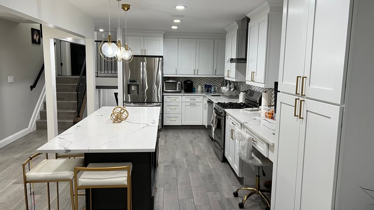Modern white kitchen with island, stainless steel appliances, gray tile flooring, and contemporary pendant lighting